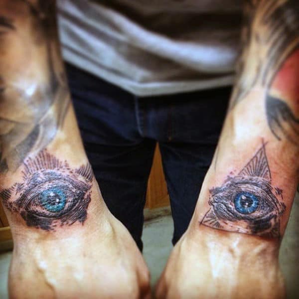 Forearms with tattoos of realistic eyes enclosed in geometric shapes