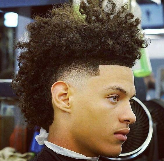 A shaggy frohawk hairstyle for men matched with a taper fade