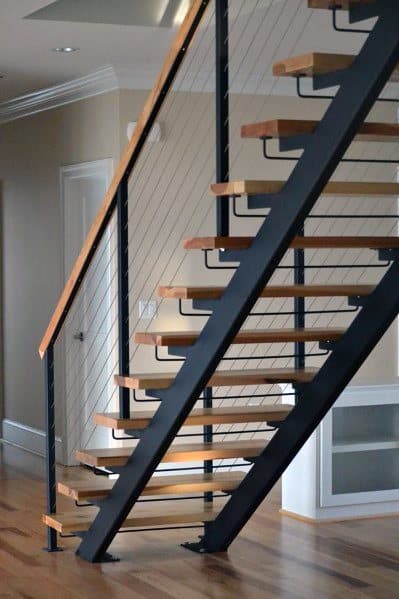 Floating wooden stairs with metal frame and cable railing in a contemporary interior design.