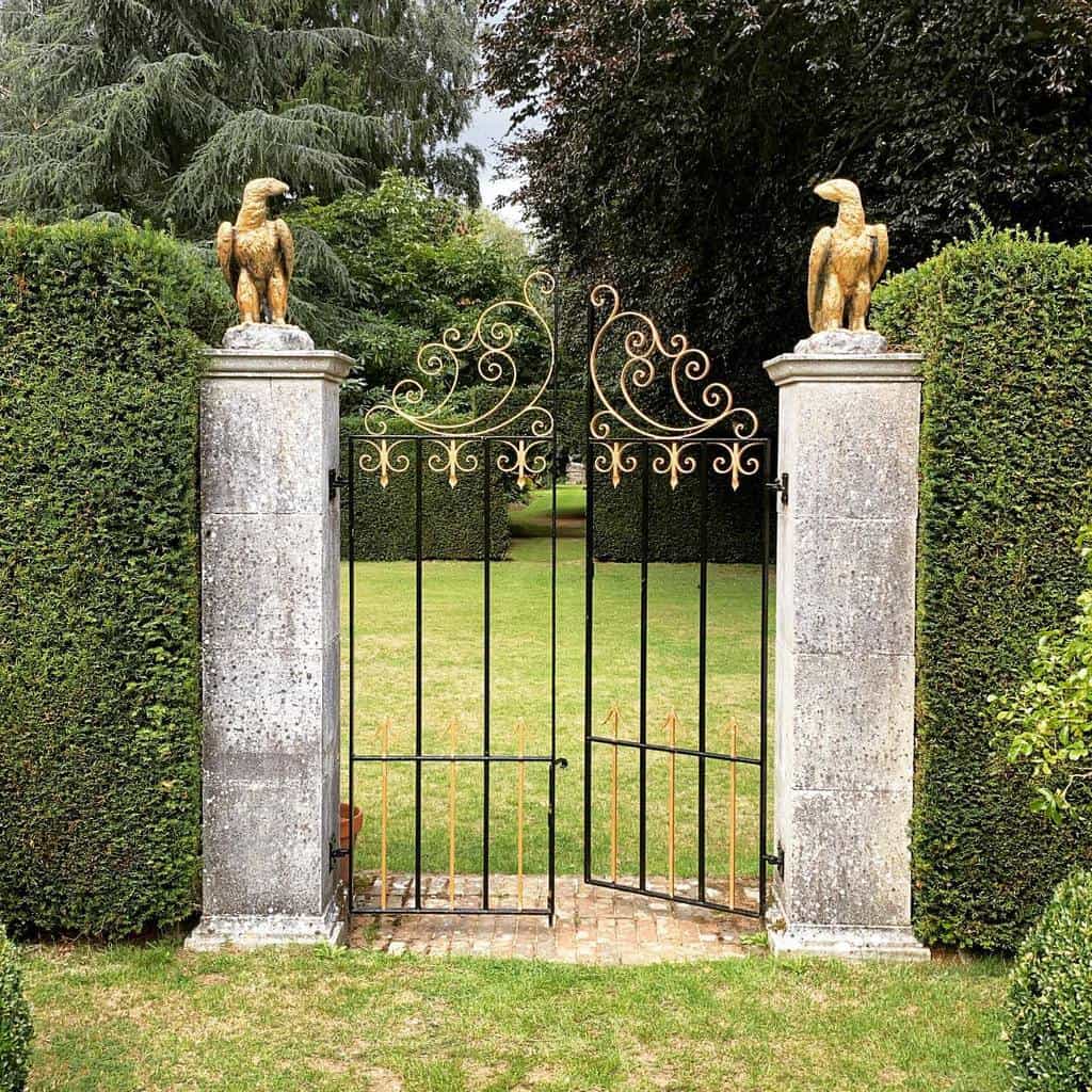regal metal gate with gold accents eagle statues stone pillars