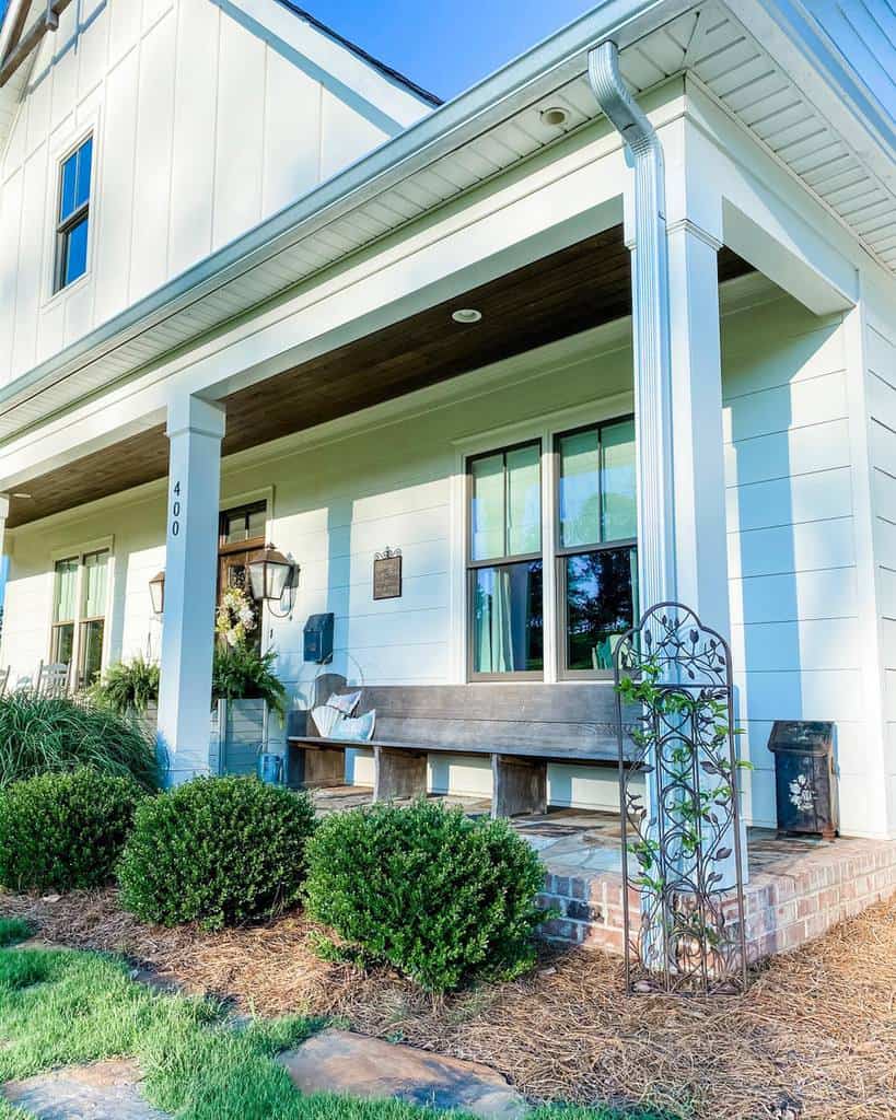 small metal garden trellis white shiplap house wood bench