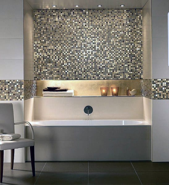 Built-in bathtub with metallic mosaic tile accent wall and warm candle lighting.