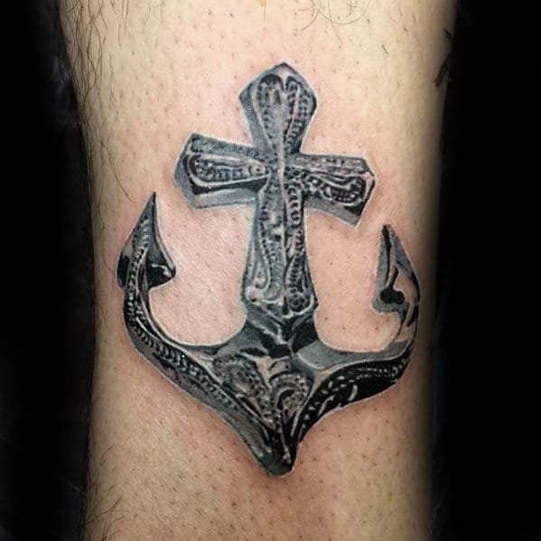 Tattoo of an intricately designed anchor with a cross at the top