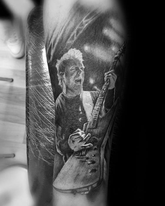 Black and grey tattoo of James Hetfield on stage mid-performance, playing guitar under concert lights with intense energy.