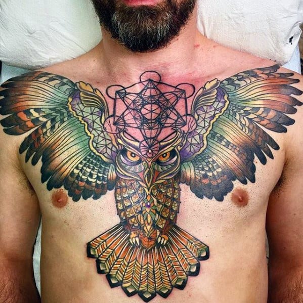 Vibrant chest tattoo of a detailed owl with outstretched wings, featuring Metatron’s Cube in black linework above its head.