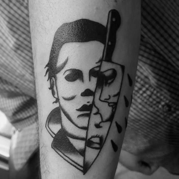 Bold black ink Michael Myers tattoo featuring a knife reflecting a terrified face, blending horror and minimalistic design.
