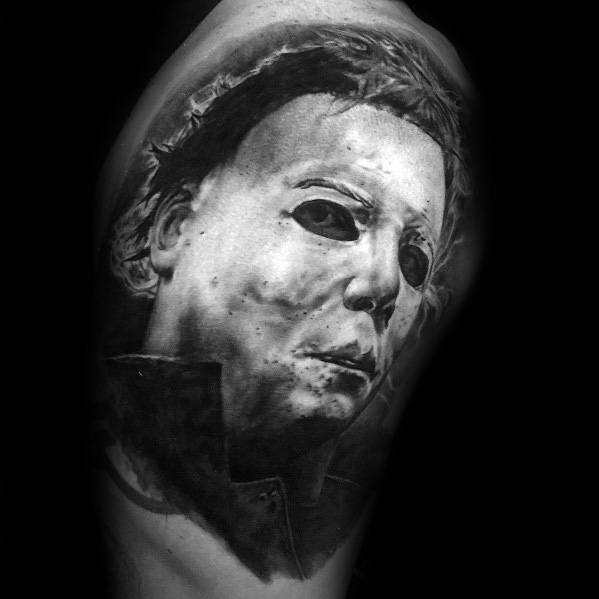 Realistic black and gray Michael Myers tattoo, showcasing his eerie mask with deep shadows for a haunting and intense horror effect.