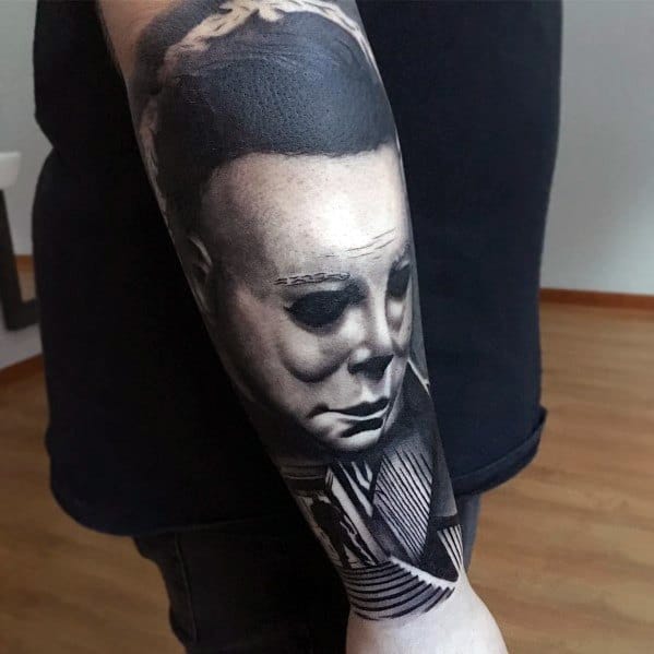 Realistic black and grey tattoo of Michael Myers' masked face, capturing his eerie expression with detailed shading.