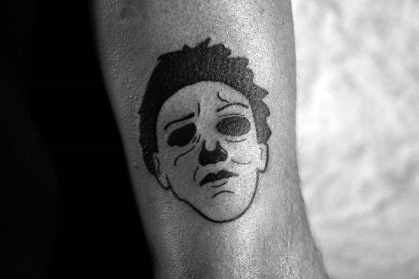 Simple black ink Michael Myers tattoo featuring his iconic mask with minimal detailing for a bold yet eerie design.