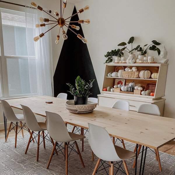 Mid-century modern boho dining room with a sleek wooden table, statement chandelier, and cozy decor.