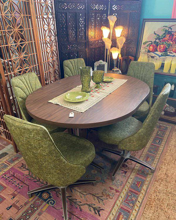Mid-century modern boho dining room with vintage green chairs, wooden table, and eclectic decor.