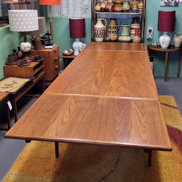 Mid-century modern expandable wooden dining table in a retro-styled room with vintage decor.