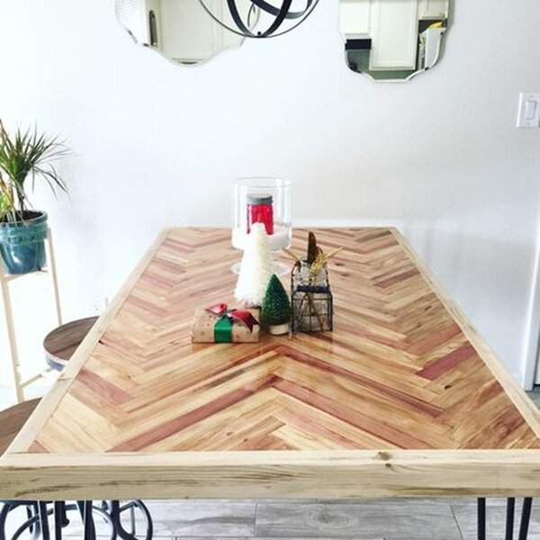 Rustic wooden dining table with a herringbone pattern, metal legs, and festive decor.