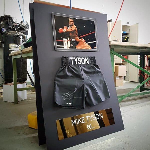 Framed display with boxing trunks, photo of a match, and "Mike Tyson" plaque