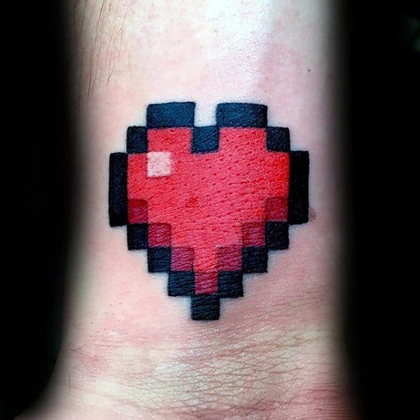 Bold pixelated red heart tattoo with a black outline, inspired by Minecraft or retro gaming, placed on the wrist.