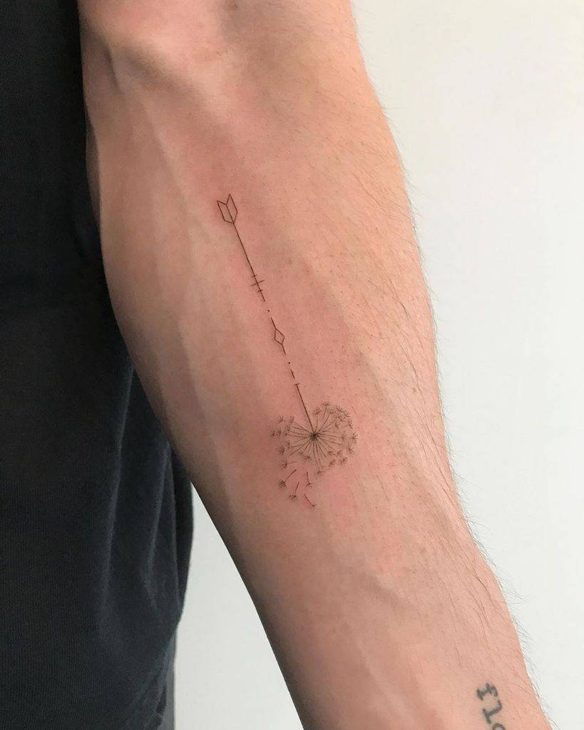 Minimalist dandelion and arrow tattoo on the forearm, symbolizing direction, dreams, and the pursuit of goals.