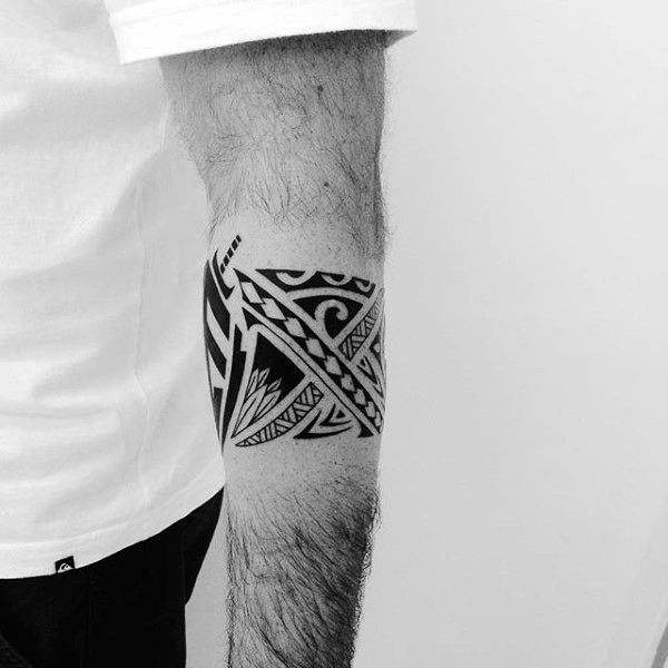 Arm with a black tribal tattoo, geometric and wave designs