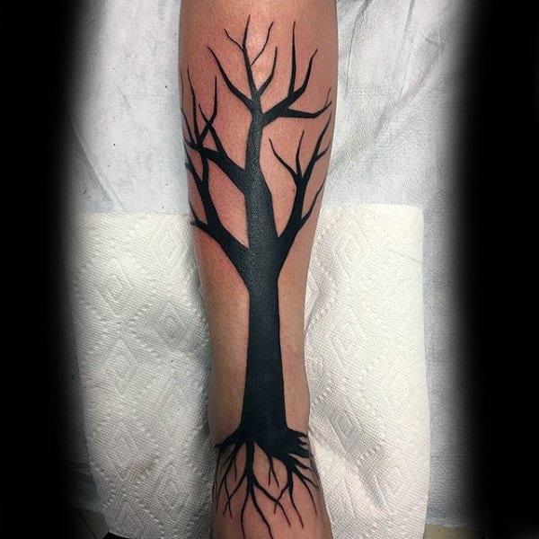 Tattoo of a leafless black tree with roots on an arm