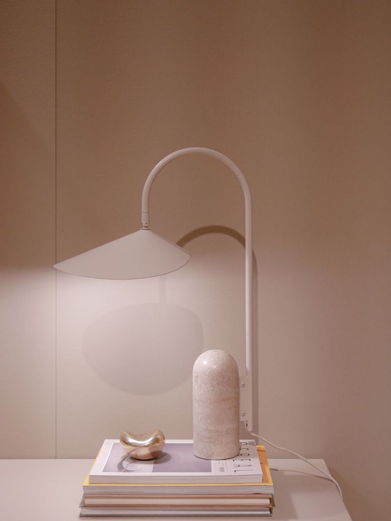 Simple bedside setup with neutral-tone lamp, books, and minimalist decor.