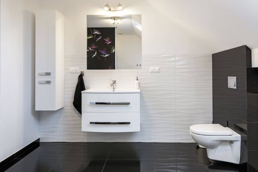 Modern minimalist bathroom with black and white tiles, sleek vanity, and floral wall decor.