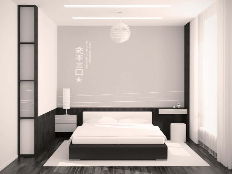 Minimalist bedroom with modern black and white design, low-profile bed, and pendant light.