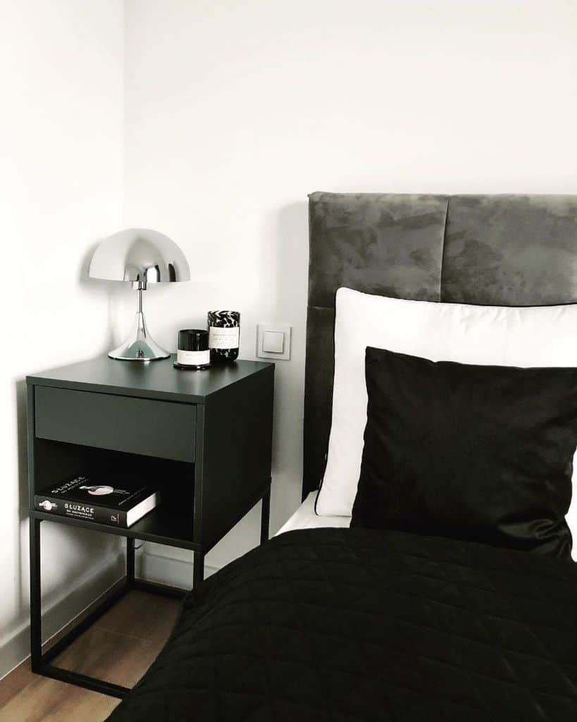 Minimalist bedroom with black bedding, gray headboard, and modern black bedside table.