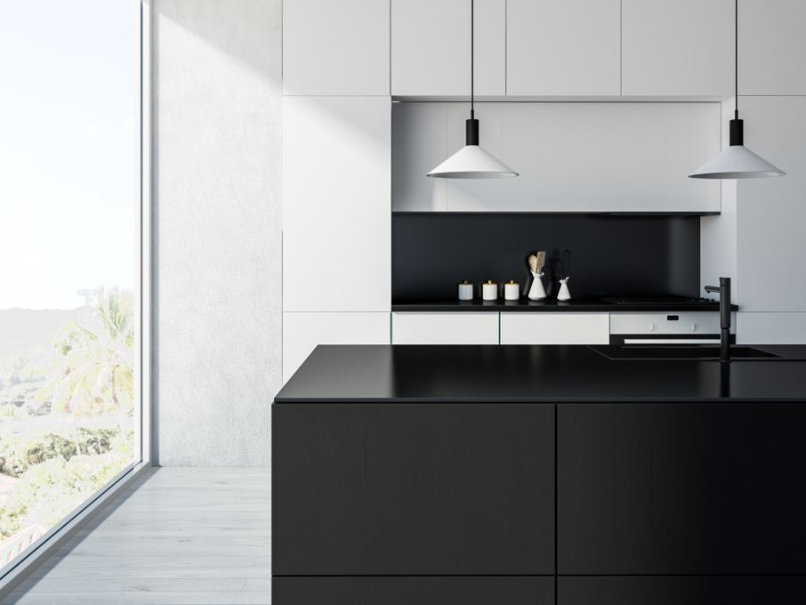 Minimalist kitchen with black island, white cabinets, and pendant lights.