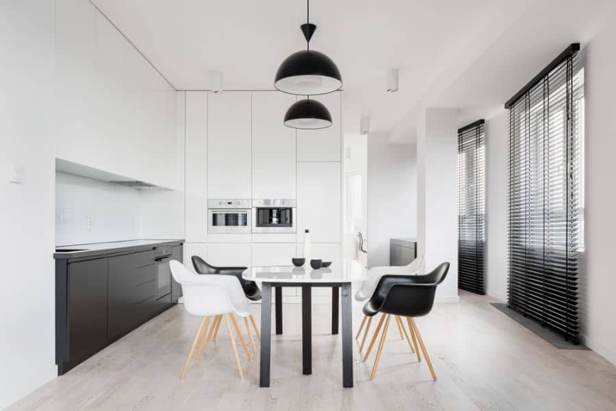 Minimalist kitchen with black lower cabinets, white upper cabinets, and dining table.