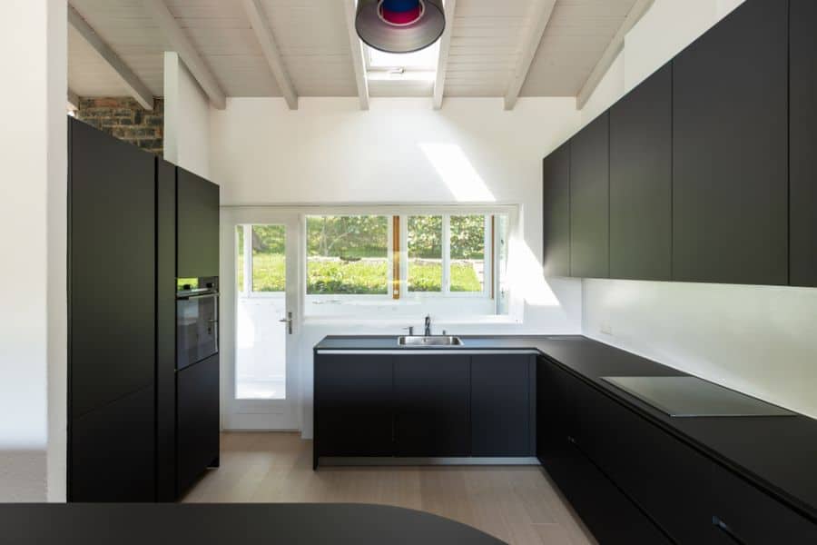 Modern kitchen with matte black cabinets, white walls, and a skylight ceiling.