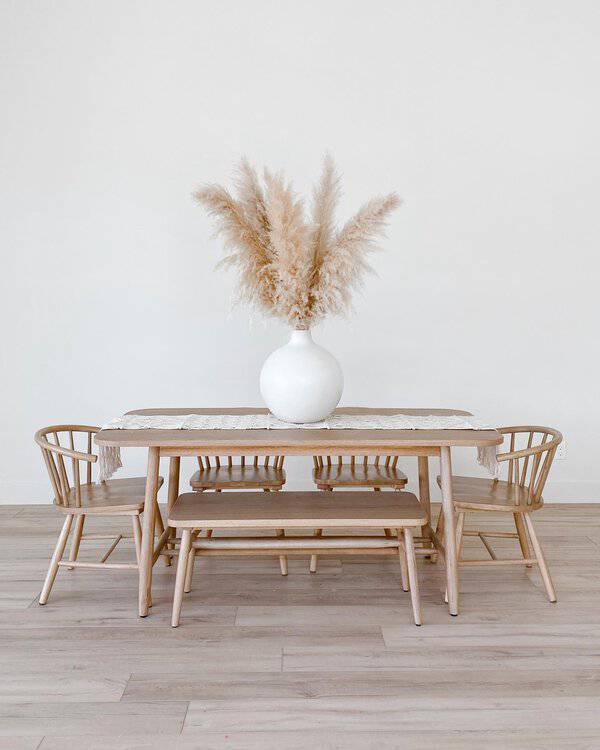 Minimalist boho dining room with light wood furniture and a pampas grass centerpiece.