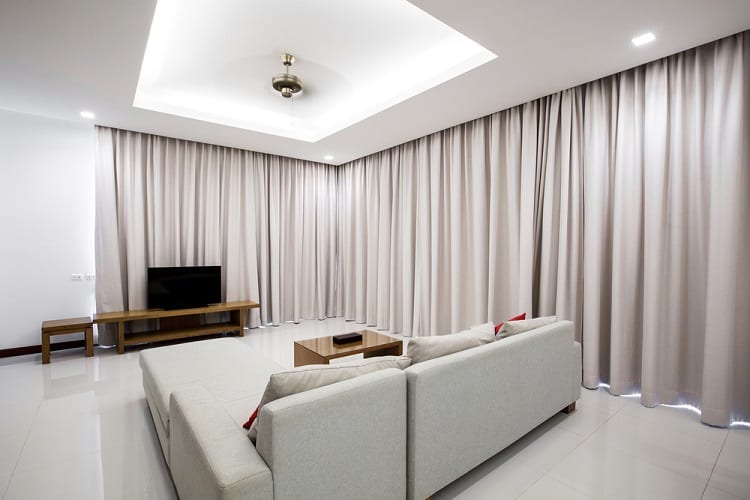 The ceiling features a minimalist design with recessed cove lighting, creating a calm, cozy atmosphere in the spacious living room