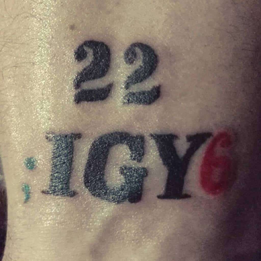 Minimalist tattoo with '22' above 'IGY6,' featuring a blue semicolon and red 6, symbolizing support and awareness