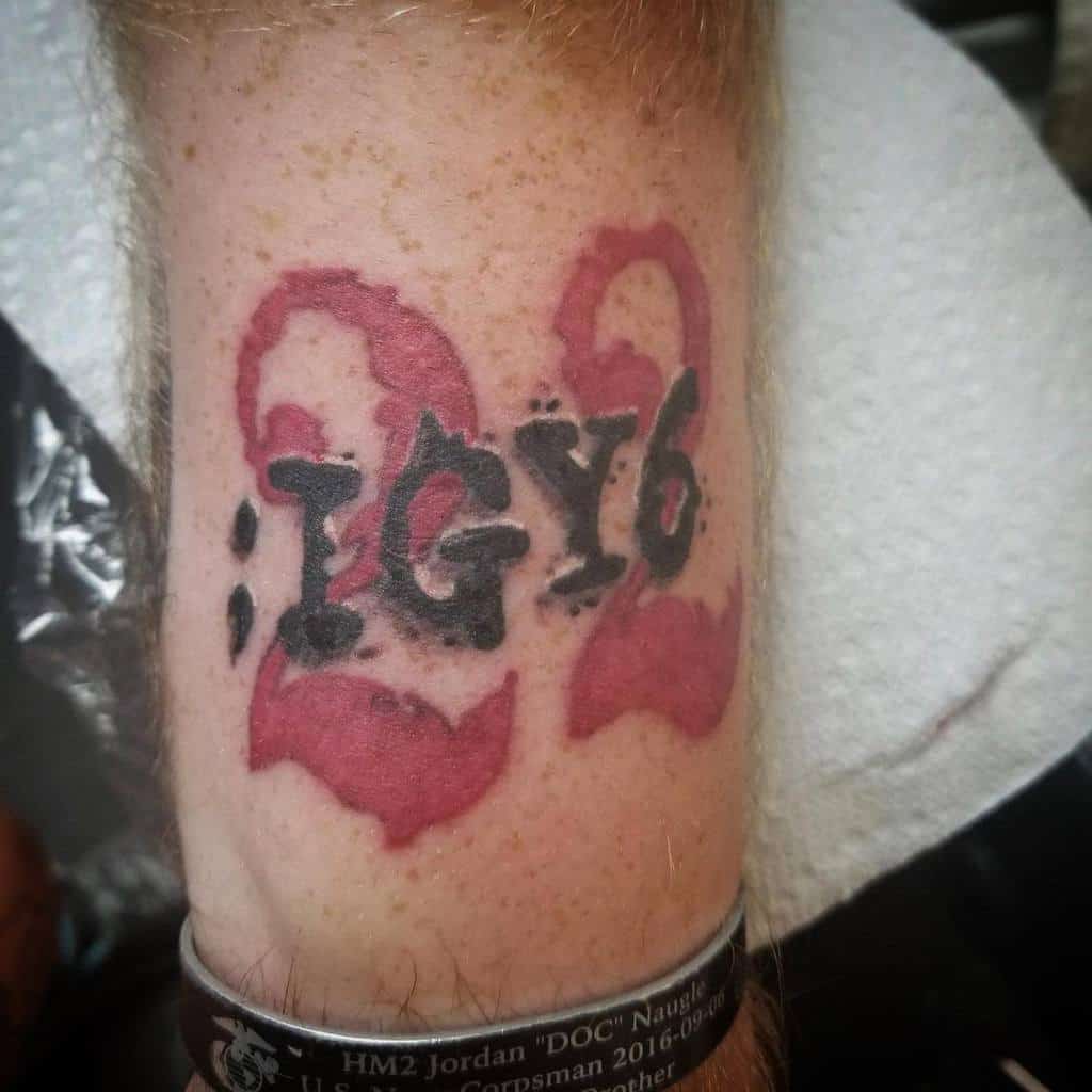 Forearm tattoo featuring ';IGY6' in bold black ink over a red '22,' symbolizing veteran support and awareness