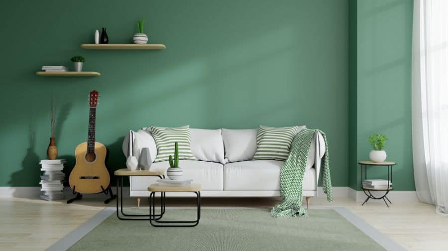 green accent wall living room with gray sofa and guitar 