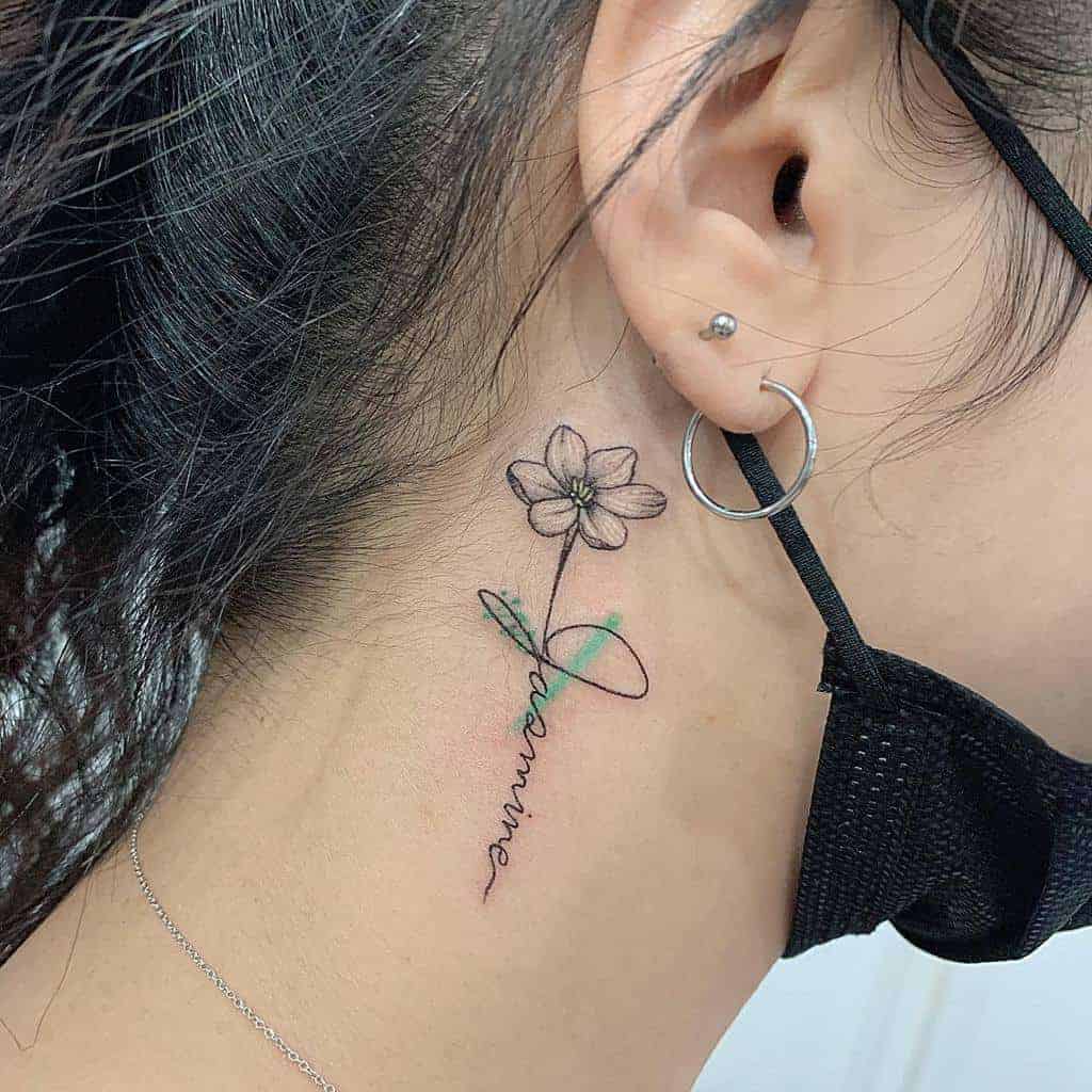 A delicate flower tattoo with the name "Jasmine" is inked behind a woman's ear