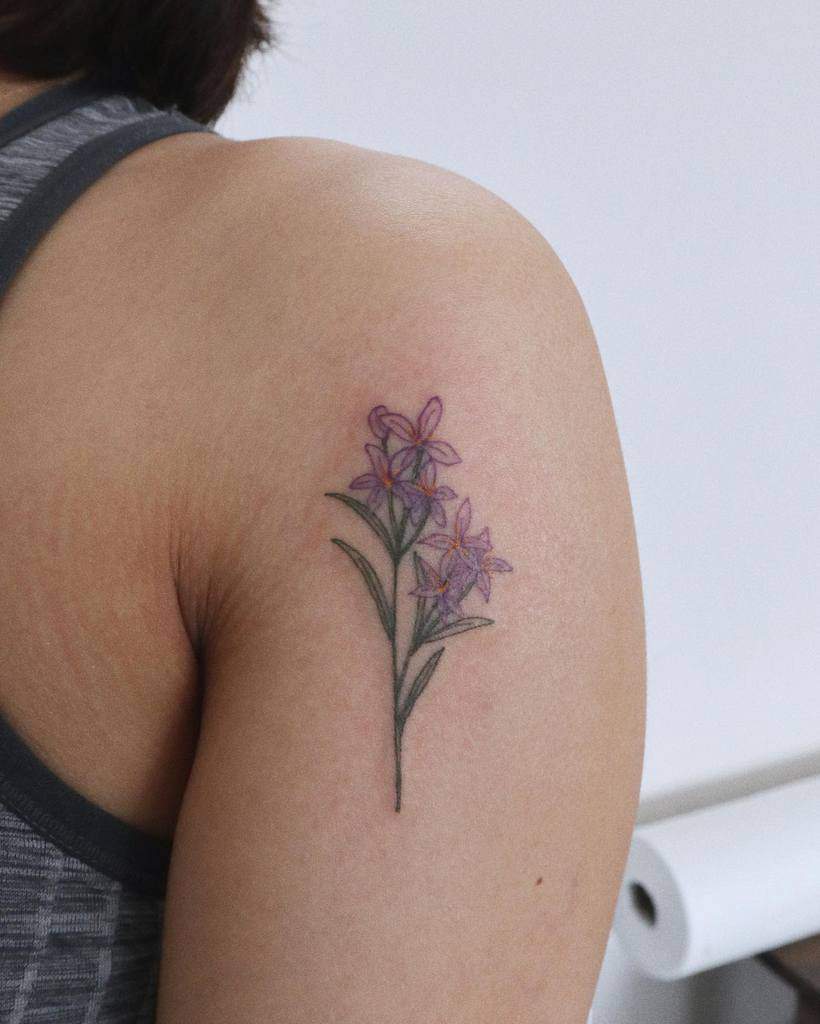 Purple floral jasmine tattoo on a person's upper arm