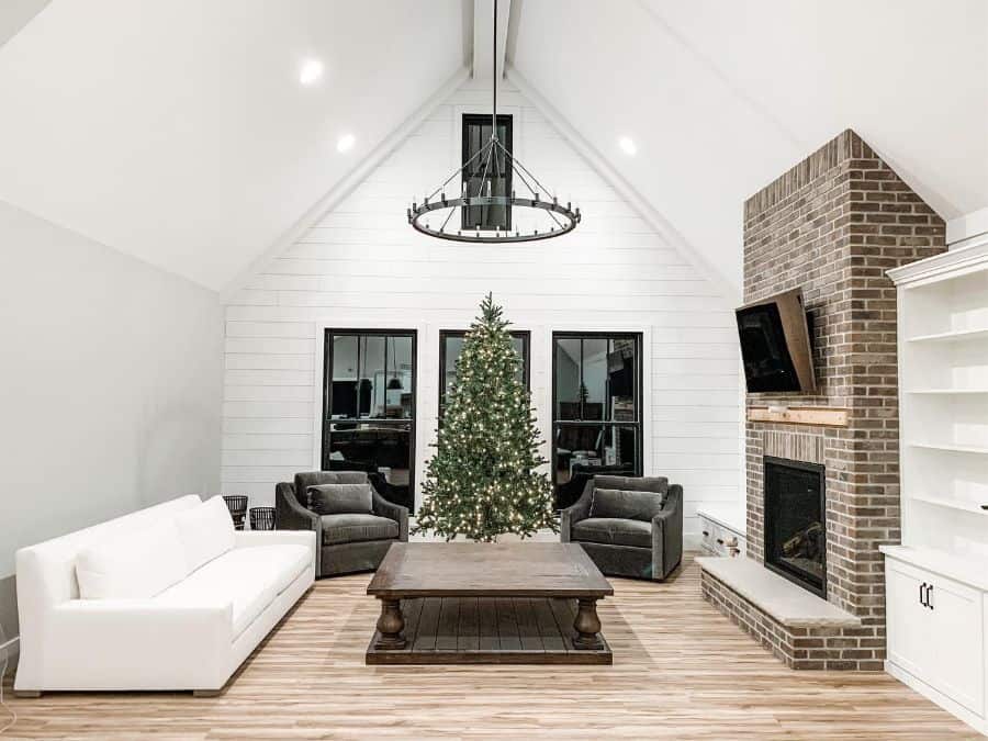 high ceiling simple living room brick fireplace white sofa chandelier christmas tree