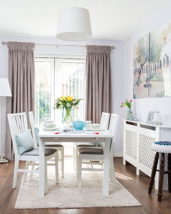 Bright dining room with soft gray curtains, white furniture, and a cozy rug for a fresh look.