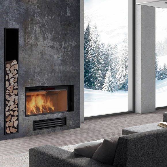 Modern concrete fireplace with firewood storage, large windows, and snowy forest views.