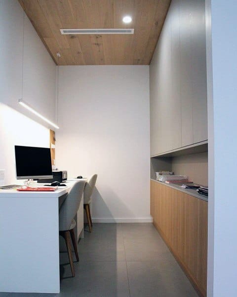 Minimalist home office with wood accents, white desk, and built-in storage cabinets.