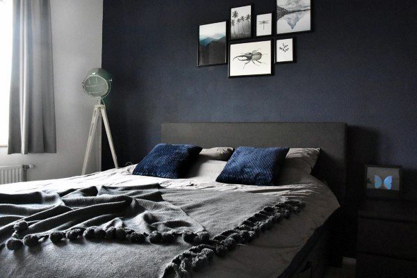 Minimalist navy bedroom with gallery wall, gray bedding, and a modern floor lamp.