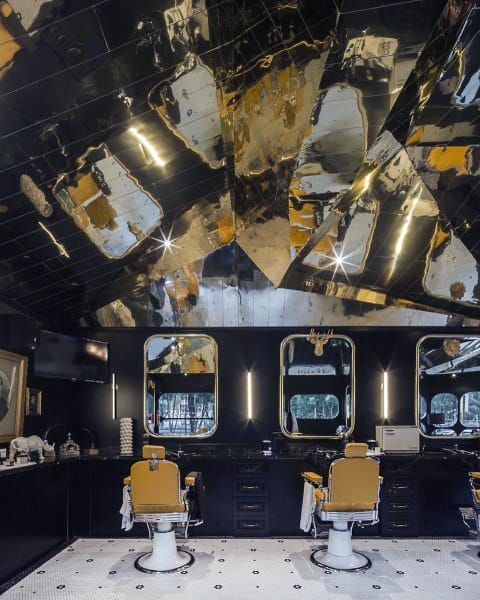 Barbershop with mirrored ceiling, yellow vintage chairs, and sleek black workstation design.