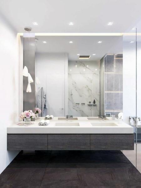 Floating double sink vanity with large mirror, recessed lighting, and marble shower in modern bathroom.