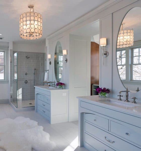 Elegant bathroom with oval mirrors, soft lighting, and walk-in glass shower.