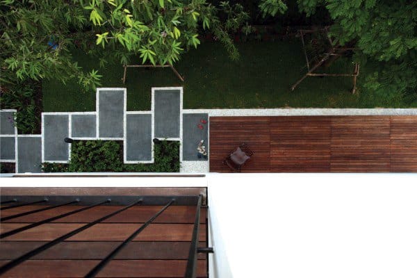 Aerial view of modern backyard with geometric stone pathways, wooden deck, and green lawn.