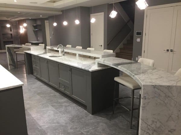 Elegant marble bar top with white seating and pendant lighting in a sleek, modern kitchen.