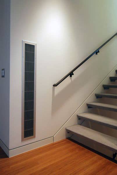 Staircase with light walls, slim baseboard, and vertical wall vent near wooden flooring.