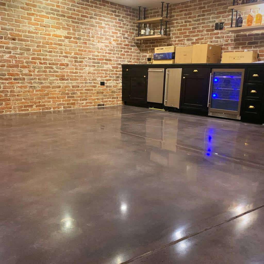 Modern basement with exposed brick walls, polished concrete floors, and black cabinetry.