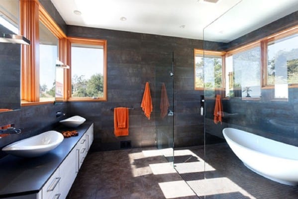 Modern bathroom with glass shower, freestanding tub, and orange accessories