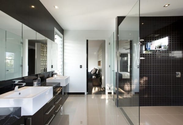 Modern bathroom with dual sinks, large mirrors, and a glass-enclosed shower